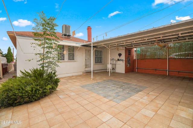 rear view of property featuring central air condition unit, fence, a patio, and stucco siding