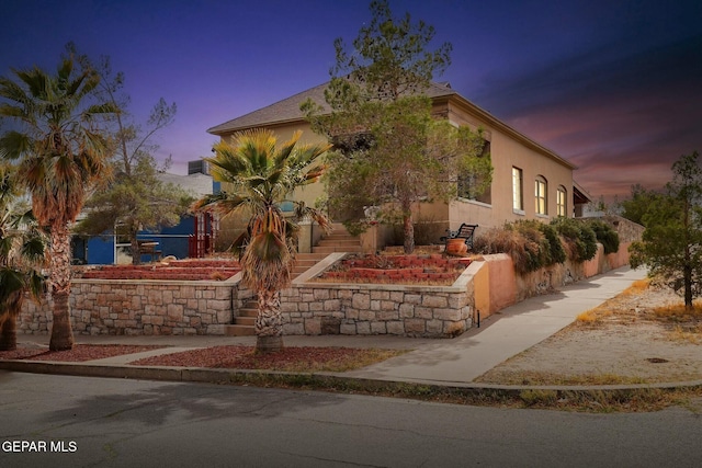 view of front facade featuring stairs and stucco siding