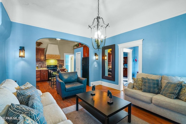 living area with dark wood-style floors, arched walkways, and a chandelier