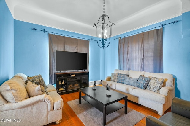 living area with crown molding, a chandelier, and wood finished floors