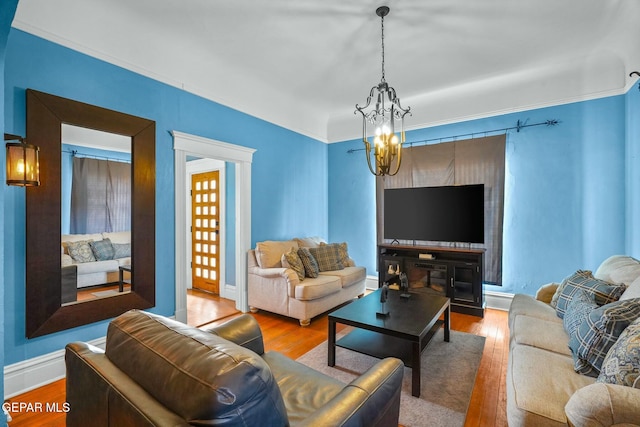 living room with baseboards, crown molding, hardwood / wood-style flooring, and an inviting chandelier