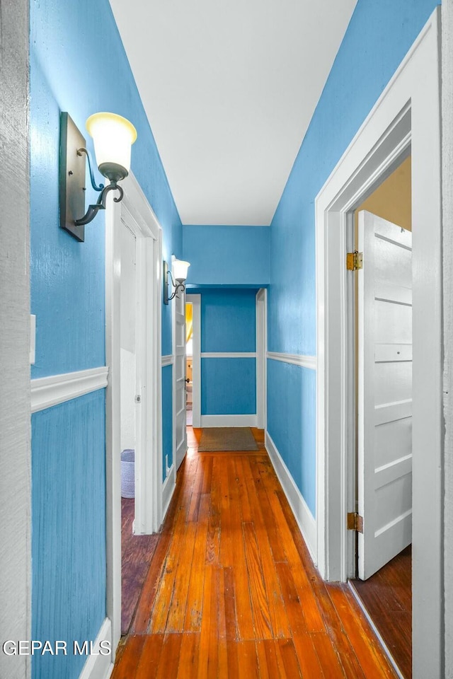 hallway with a wainscoted wall and hardwood / wood-style floors