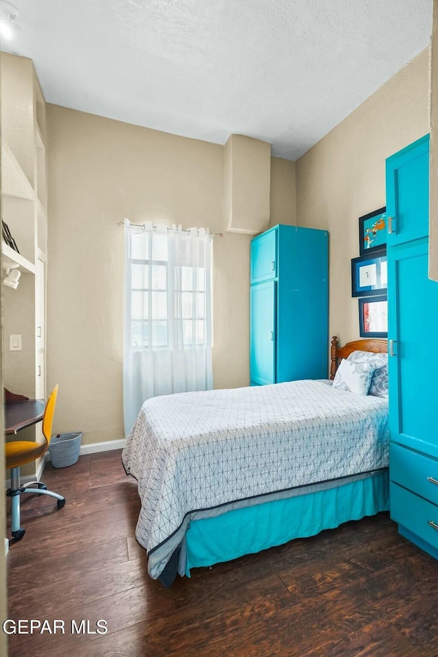 bedroom with a textured ceiling, baseboards, and wood finished floors