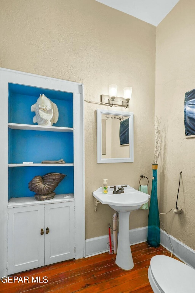 bathroom with wood finished floors, toilet, and baseboards