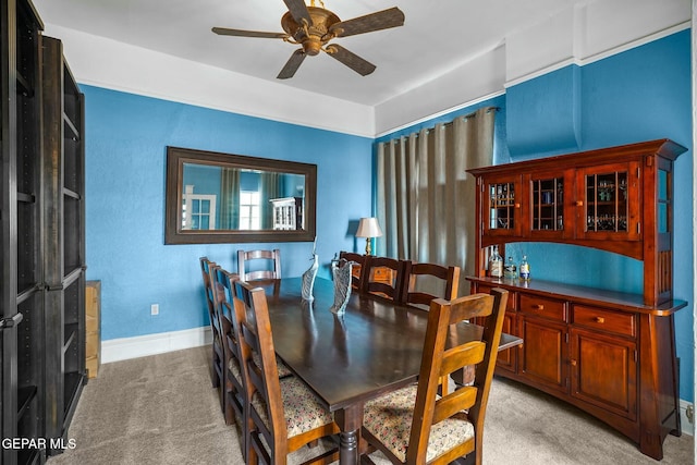 dining space with light colored carpet, ceiling fan, and baseboards