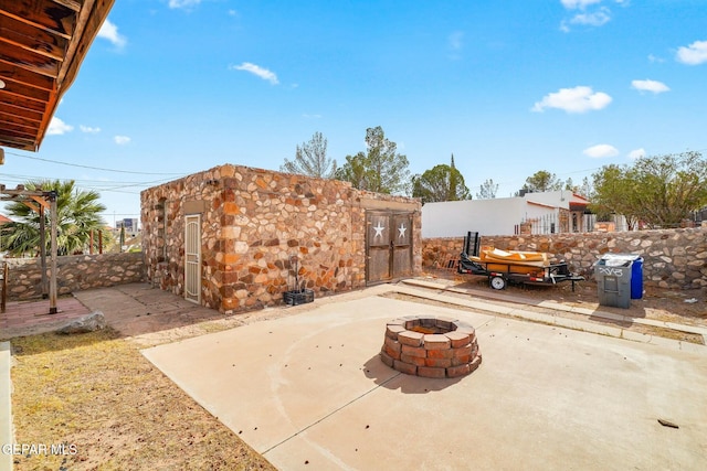 view of patio featuring an outdoor fire pit, fence, and an outdoor structure