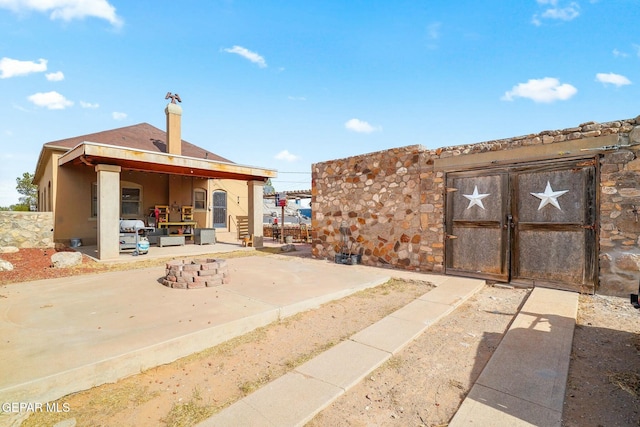 rear view of house featuring a fire pit, a patio, and a gate