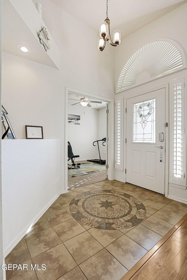 entrance foyer with baseboards and ceiling fan with notable chandelier