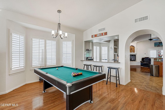 recreation room with arched walkways, visible vents, vaulted ceiling, and wood finished floors