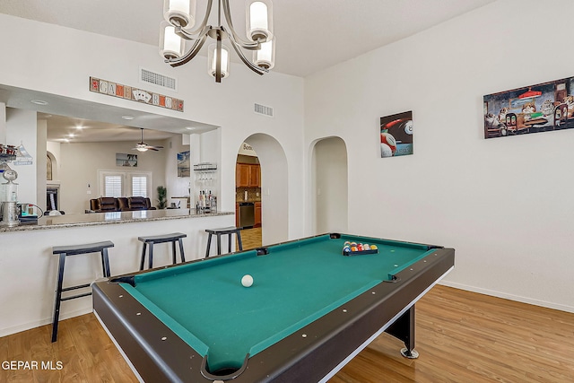 game room featuring visible vents, arched walkways, wood finished floors, and ceiling fan with notable chandelier