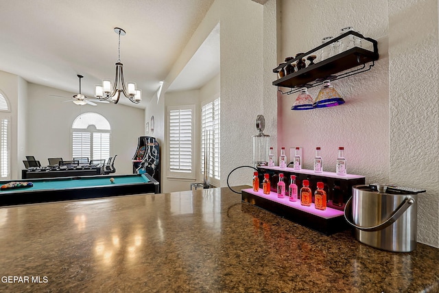 bar featuring a textured wall, hanging light fixtures, and ceiling fan with notable chandelier