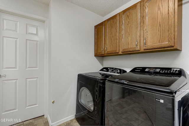 clothes washing area with cabinet space, washer and clothes dryer, baseboards, and a textured ceiling