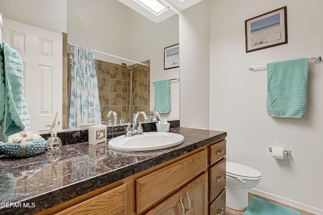 bathroom with a skylight, a tile shower, vanity, and toilet