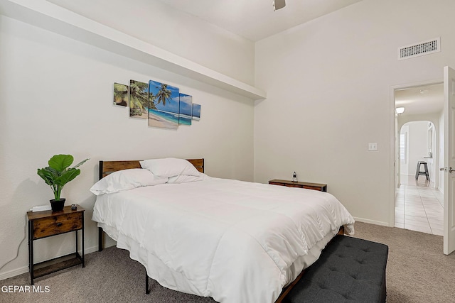 carpeted bedroom featuring visible vents, arched walkways, baseboards, and tile patterned floors