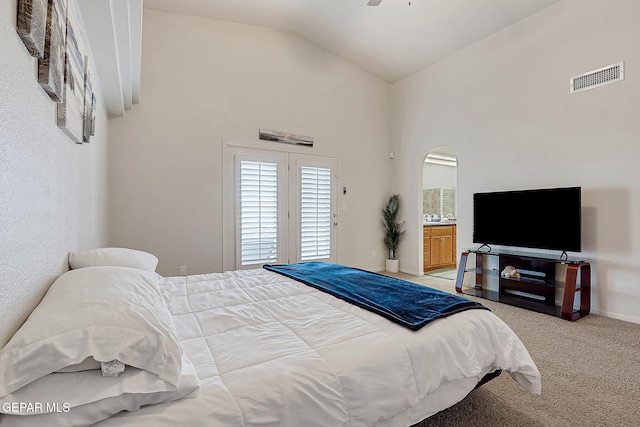 bedroom featuring visible vents, arched walkways, light colored carpet, ensuite bathroom, and high vaulted ceiling