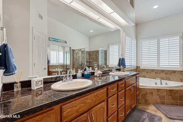 bathroom with a whirlpool tub, double vanity, a stall shower, and a sink