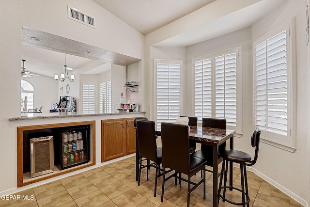 dining room featuring beverage cooler, visible vents, wet bar, vaulted ceiling, and light tile patterned flooring