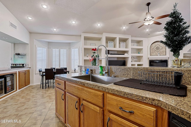 kitchen featuring tile countertops, light tile patterned floors, visible vents, a sink, and a tile fireplace