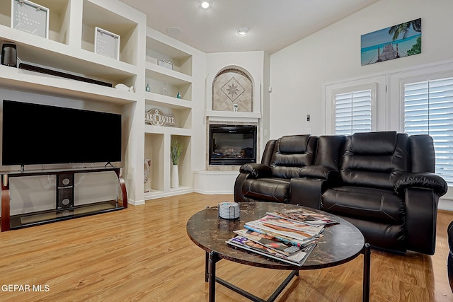 living area with wood finished floors, a glass covered fireplace, and built in features