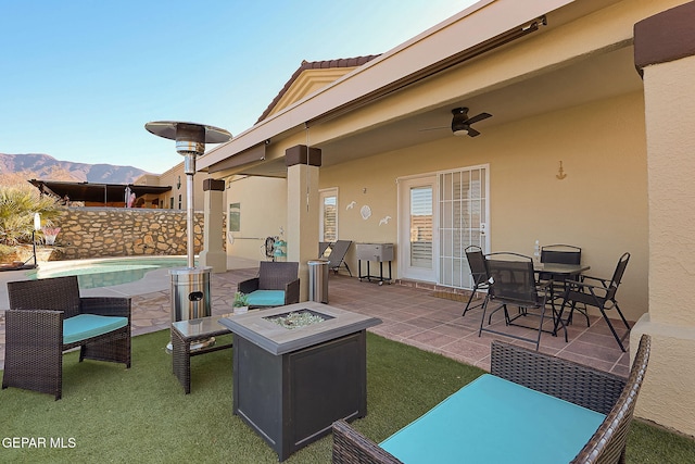 view of patio / terrace featuring a fenced in pool, outdoor dining area, a ceiling fan, an outdoor fire pit, and a mountain view