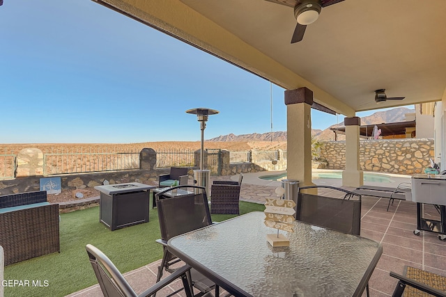 view of patio / terrace with a fenced backyard, a mountain view, a ceiling fan, a fenced in pool, and outdoor dining space