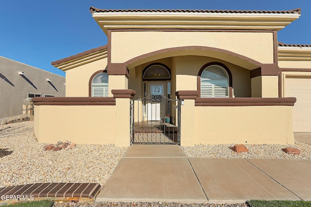 view of front of property featuring a fenced front yard, a gate, a tiled roof, and stucco siding