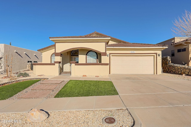 mediterranean / spanish-style home featuring a garage, a tiled roof, a fenced front yard, and stucco siding