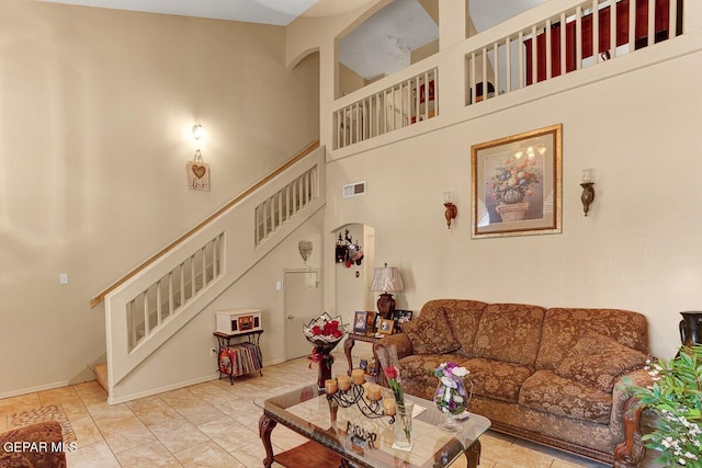 living area featuring a towering ceiling, stairs, and visible vents