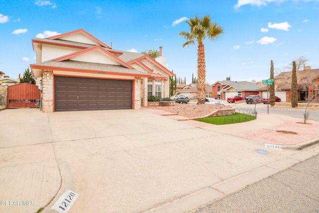 traditional home with a gate, brick siding, a garage, and driveway