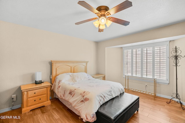 bedroom with ceiling fan, baseboards, and light wood-style floors