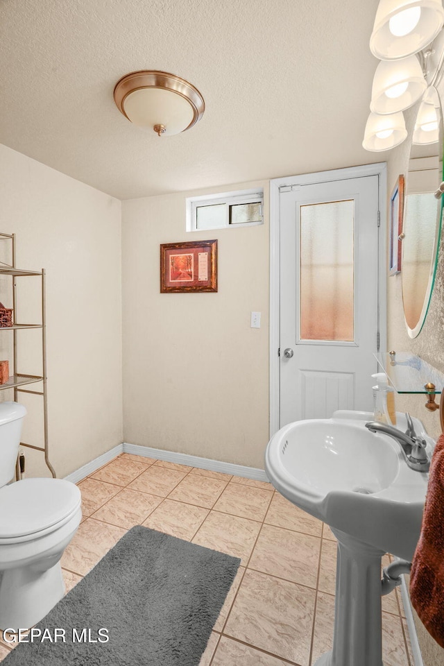 bathroom featuring baseboards, a textured ceiling, and toilet