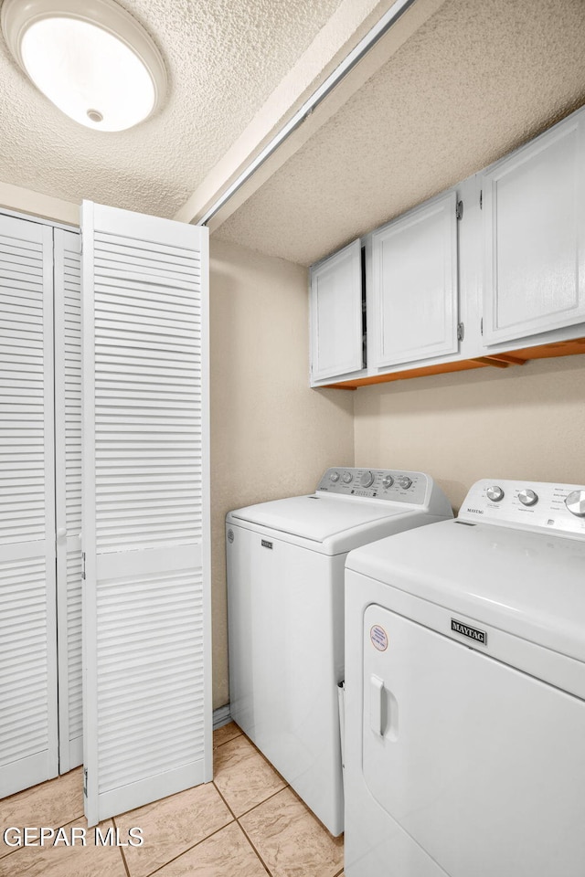 laundry room featuring cabinet space, a textured ceiling, and washing machine and dryer