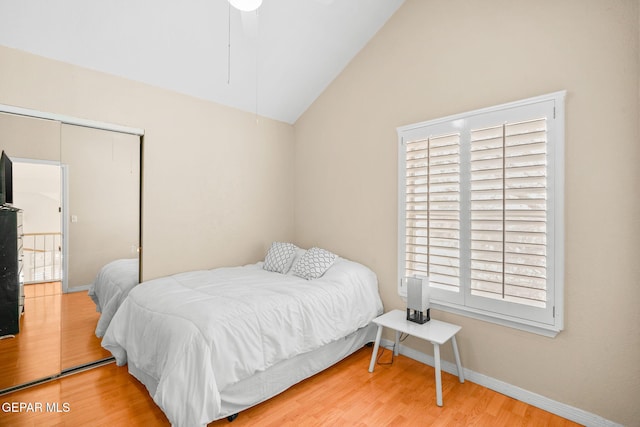 bedroom with baseboards, lofted ceiling, a closet, and wood finished floors