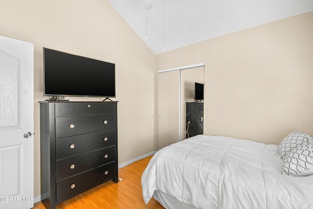 bedroom with vaulted ceiling, baseboards, a closet, and light wood finished floors