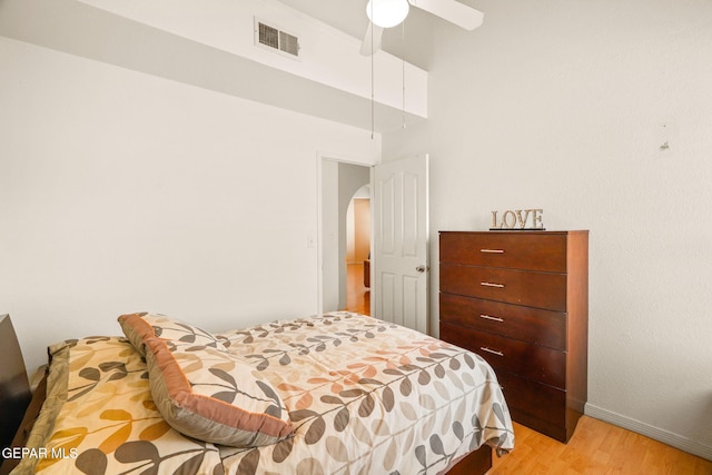 bedroom with light wood finished floors, visible vents, ceiling fan, baseboards, and arched walkways