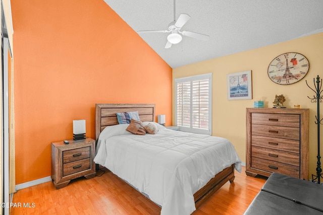 bedroom with baseboards, a textured ceiling, light wood-style floors, and lofted ceiling