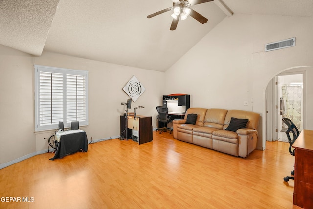 living area with visible vents, arched walkways, beam ceiling, and wood finished floors