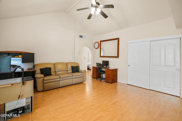 living area featuring visible vents, beamed ceiling, arched walkways, light wood finished floors, and ceiling fan