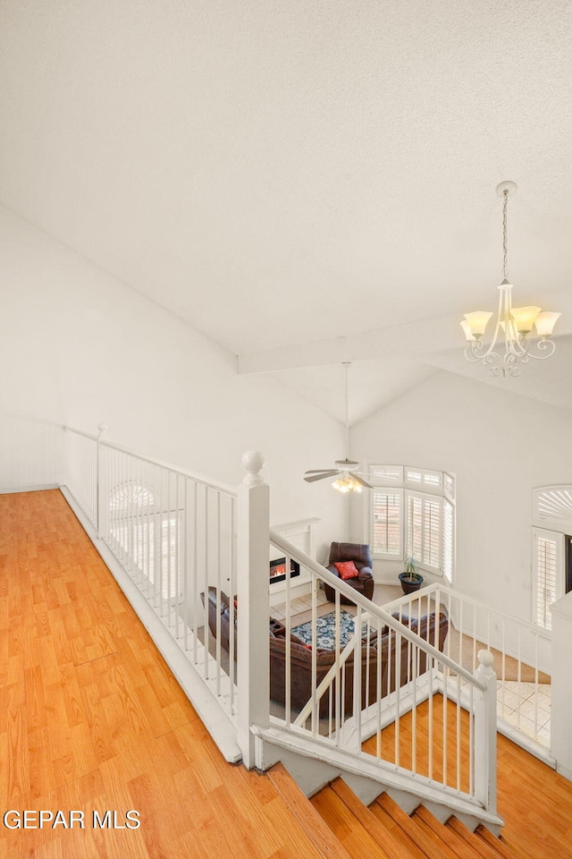 hall with vaulted ceiling, a notable chandelier, a healthy amount of sunlight, and wood finished floors