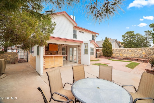 rear view of property featuring a patio, outdoor dining area, french doors, and fence