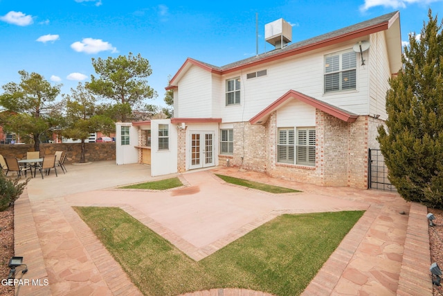 back of house with french doors, brick siding, a patio area, and fence