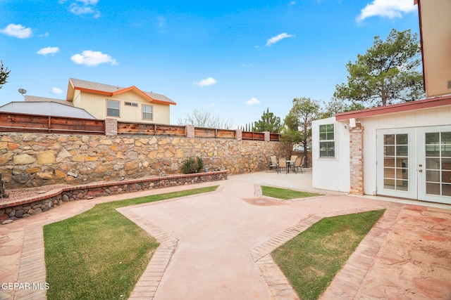 view of yard featuring a patio area, french doors, and a fenced backyard