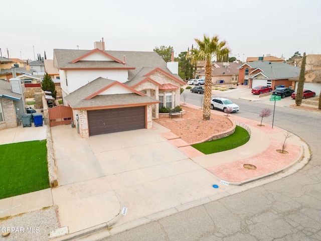 view of front of property featuring a gate, a residential view, concrete driveway, a garage, and brick siding