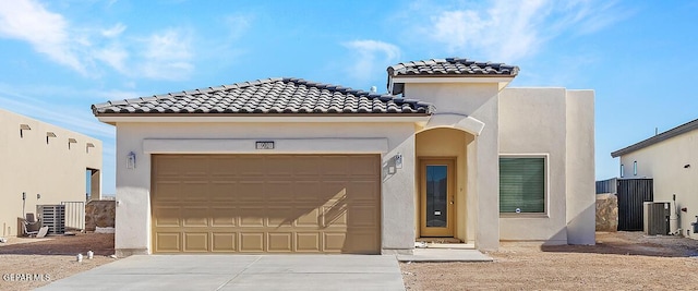 mediterranean / spanish-style home with a garage, central AC, driveway, a tiled roof, and stucco siding