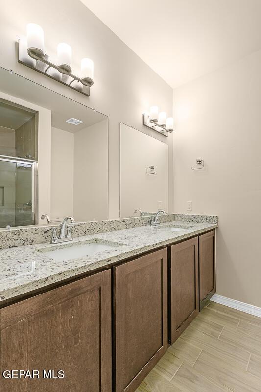 bathroom featuring an enclosed shower, visible vents, a sink, and double vanity