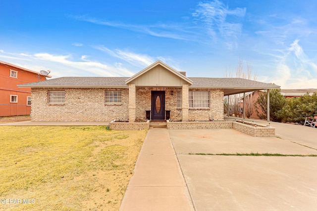 single story home with roof with shingles, a front lawn, and brick siding