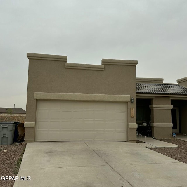 view of front of home featuring a tile roof, stucco siding, concrete driveway, and a garage