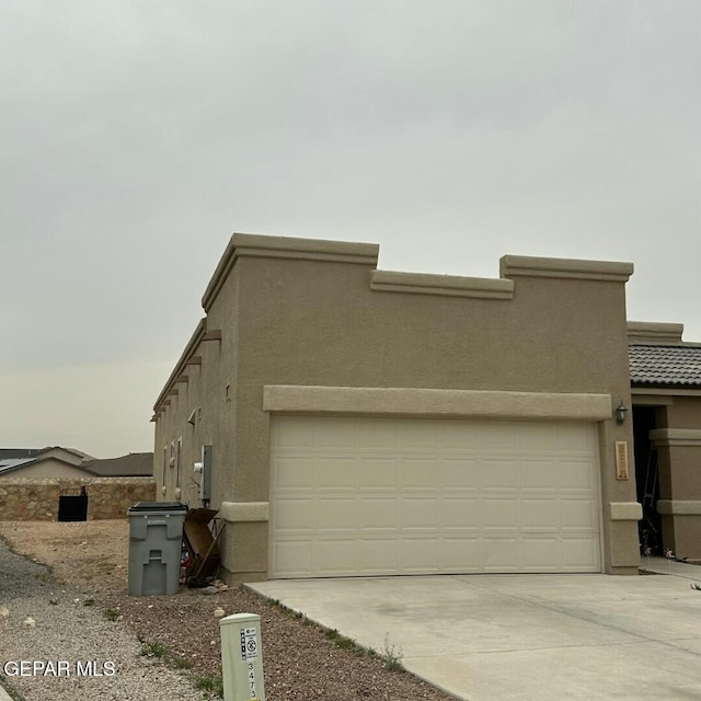 view of front of house featuring stucco siding, a garage, and driveway