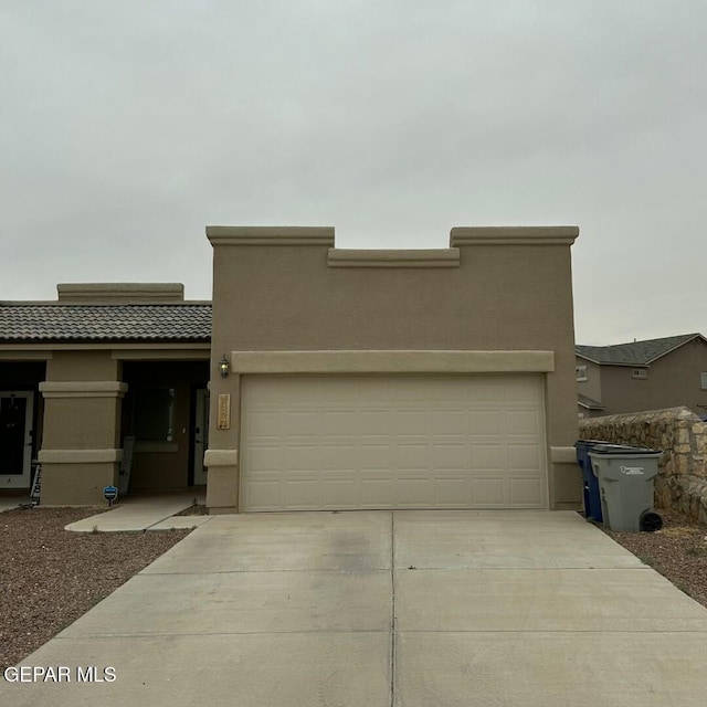 view of front facade with stucco siding, concrete driveway, and an attached garage