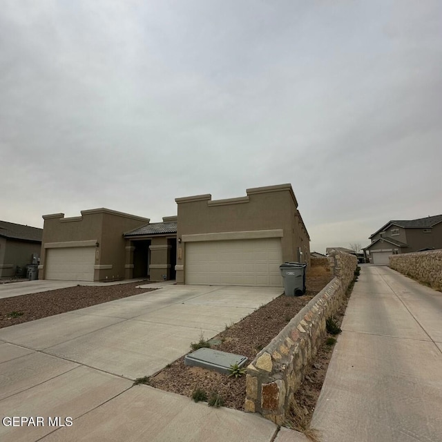 view of front facade with concrete driveway, an attached garage, and stucco siding